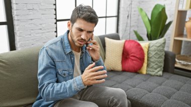 Modern bir oturma odasındaki telefon görüşmesinde sakallı genç bir İspanyol endişeli görünüyor..