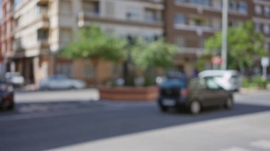 Arka planda binalar, arabalar ve yeşilliklerle bulanık şehir manzarası. Bokeh efektli yumuşak, bulanık bir görüntü yaratıyor..