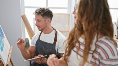 Işıkla dolu bir stüdyo içinde resim yapan yaratıcı erkek ve kadın. Sanat, takım çalışması ve eğitim..