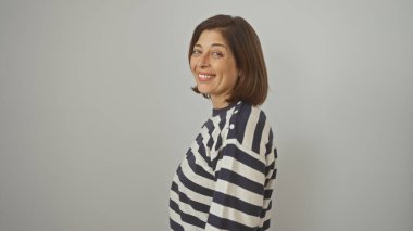 Çizgili gömlekli neşeli, orta yaşlı bir İspanyol kadın beyaz bir arka plana karşı poz veriyor, kendine güveni ve özgüveni tam..