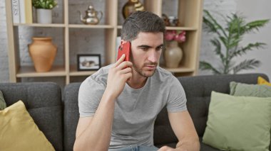 Çekici, genç İspanyol bir adam güzel dekore edilmiş bir oturma odasında otururken bir telefon görüşmesi yapıyor..