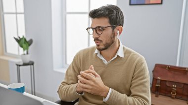 Modern ofiste sakallı, kablosuz kulaklık takan yakışıklı bir İspanyol.