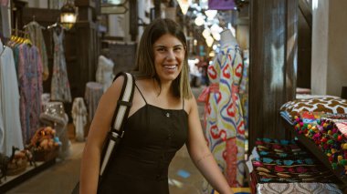 Dubai 'de geleneksel çarşıyı keşfeden gülümseyen genç kadın renkli tekstil ve Arap dekoruyla