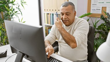 Ofis ortamında çalışan ve konuşan orta yaşlı İspanyol bir adam..