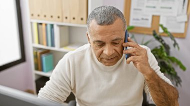 İspanyol orta yaşlı adam modern ofiste telefonla konuşuyor, profesyonellik ve iletişim sergiliyor..