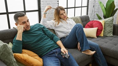 Bir kadın ve bir erkek, modern bir oturma odasındaki bir kanepede rahatlar, rahatlık ve rahatlık yayarlar..