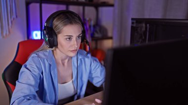 Gece karanlık bir oyun odasında kulaklık takan odaklanmış sarışın bir kadın ilginç bir deneyimi canlandırıyordu..