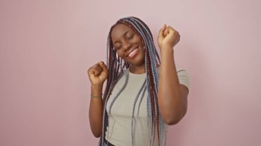 Örgü örmüş neşeli bir Afro-Amerikalı kadın pembe bir arka planda dans ediyor, mutluluk ve güzellik saçıyor..