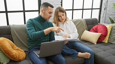 Bir çift, modern oturma odalarında birlikte dokümanları inceleyerek, ortaklık duygusunu ve ev yönetimini aktarıyorlar..