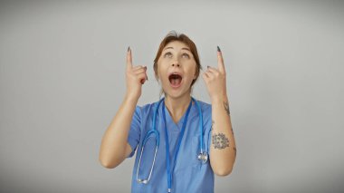Steteskopla önlüklü, beyaz bir arka plana bakan şaşırmış genç bir kadın..