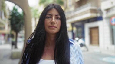 Çekici İspanyol esmer kadın şehir dışındaki bir sokakta duruyor. Arka planı bulanık..