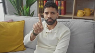 Evinde öfkeli, genç, İspanyol bir adam 'hayır' işareti yapıyor, büyük bir hoşnutsuzluk ve ciddi bir uyarıda bulunuyor.