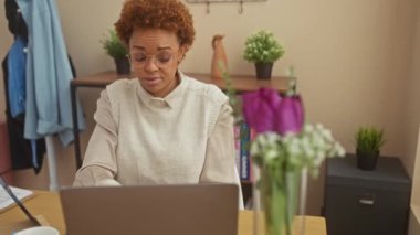 Tarzıyla aşağılayan, gülen Afro-Amerikan kadın evde oturuyor, parmaklarıyla alnına 