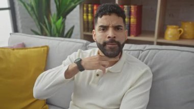 Öfkeli genç İspanyol bir adam boğazında bıçakla tehdit jesti sergiliyor. Evdeki kesme hareketinde saldırganlık ve şiddet gösteriyor.