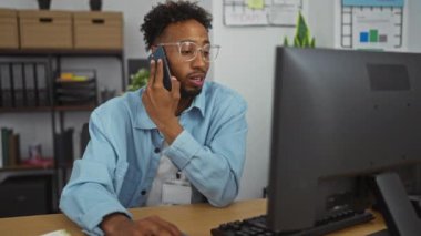 Ofisteki masada sakallı ve gözlüklü Afrikalı Amerikalı bir adam.