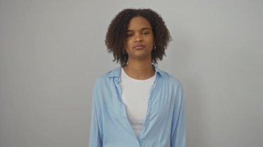 Genç Afro-Amerikalı kadın gömleğini giymiş, dili dışarıda duruyor ve izole edilmiş beyaz arka planda komik ve mutlu bir ifade sergiliyor.