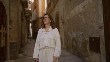 Güzel, genç, İspanyol bir kadın, neşeli bir gülümsemeyle Bari, İtalya 'nın eski sokaklarını keşfediyor. Etrafındaki tarihi mimariyi ve yaşlanmış taş duvarları takdir ediyor..