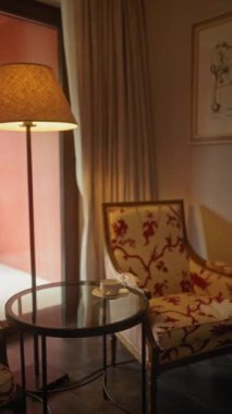 Lamba ışığı ve botanik çizimleri olan rahat bir odada şık bir koltuk ve masa..