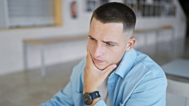 Modern bir üniversite ortamında kapalı alanda düşünen yakışıklı bir genç..