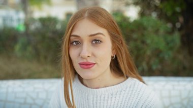 Kızıl saçlı, açık havada beyaz bir kazak giyen beyaz tenli genç bir kadının portresi..