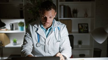 Ofiste geç saatlere kadar çalışan genç İspanyol erkek doktor profesyonelliği ve bağlılığı yansıtıyor..