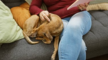 Orta yaşlı bir kadın evde kitap okumaktan, köpeğini nazikçe okşamaktan, rahatlama ve arkadaşlık kurmaktan hoşlanır..