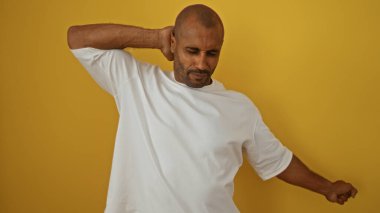 İzole edilmiş sarı bir arka plana yaslanan genç adam, sakin ve sakin bir tavır sergiliyor..