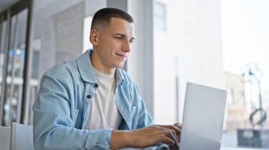 Genç İspanyol bir adam parlak bir üniversite kütüphanesinde dizüstü bilgisayarda okuyor.