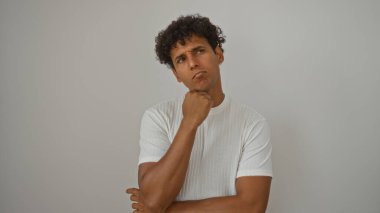Soyutlanmış beyaz bir arkaplan üzerinde düşünen genç bir İspanyol.