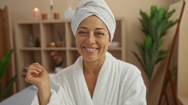 Güzellik merkezinde havlu ve bornozla gülümseyen kadın.