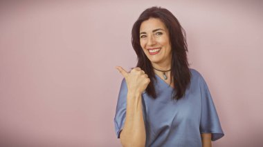 Gülümseyen orta yaşlı İspanyol kadın soyutlanmış pembe bir arka planı yan gösteriyor..