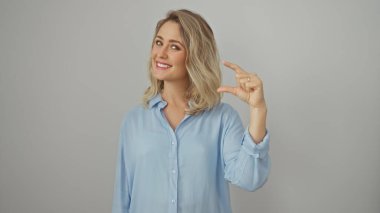Mavi gömlekli genç sarışın kadın izole edilmiş beyaz arka plana karşı küçük bir jest yapıyor.
