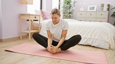 Kafkasyalı kadın yatak odasında yoga yapıyor. Dairesinde huzurlu bir atmosfer yaratıyor..
