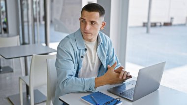 Modern bir üniversite kütüphanesinde dizüstü bilgisayarı olan yakışıklı bir İspanyol..