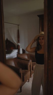 Şapkalı şık bir genç kadın, evde rahat bir ev atmosferini klasik mobilyalarla yansıtıyor..