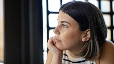 Genç ve güzel İspanyol kadın masada oturmuş restoranda ciddi ciddi bakıyor.