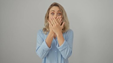 Şaşırmış, beyaz arka planda elleri ile ağzını kapatan beyaz bir kadın.