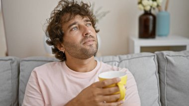 Düşünceli İspanyol adam sıcak oturma odasında kahve tutuyor..