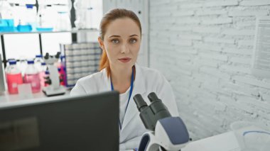 Parlak bir laboratuvar odasında örnekleri analiz eden odaklanmış genç bir bilim kadını..