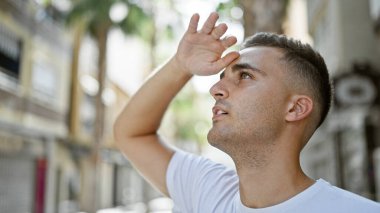 Genç bir İspanyol adam, güneşli şehir manzarasına bakarak gözlerini kapatıyor..