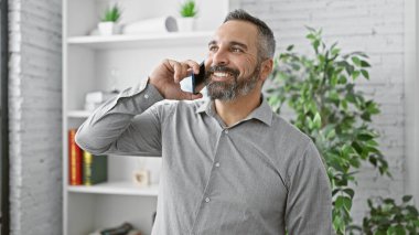 Ofiste gri sakallı, gülümseyen olgun bir İspanyol telefon görüşmesi yapıyor..