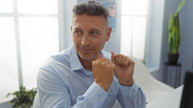 Ofiste oturan mavi gömlekli yakışıklı orta yaşlı adam.