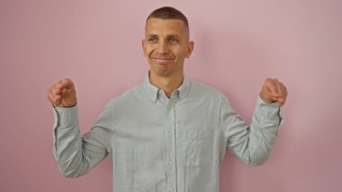 Pembe arka planda poz veren, açık mavi gömlekli yakışıklı bir genç..