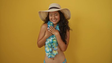 Yazın giydiği güzel Asyalı kadın elleri göğsünde izole edilmiş sarı bir arka plana gülümsüyor.
