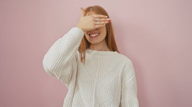 Beyaz kazaklı, gülümseyen, beyaz saçlı, pembe arka planda gözleri olan genç, beyaz bir kadın..