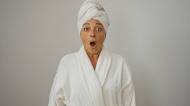 Beyaz arka planda duran esmer saçlı, orta yaşlı İspanyol kadın şaşırmış görünüyor.