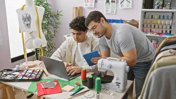 stock image Two men working together in a tailor shop, surrounded by fabric, a sewing machine, and a mannequin.