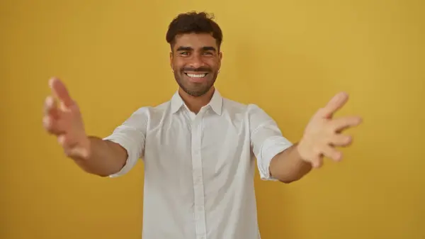 stock image Handsome man standing over yellow background extending arms for a hug while smiling