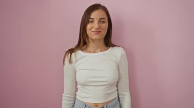 Genç sarışın kadın ayakta ve gülümsüyor mutlu mesut pembe arka planı imzala, parmaklarıyla gözlerinden bak.