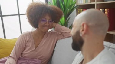 İçerde eğlenen ırklar arası bir çift, ortağına gülümseyen bir kadınla, rahat, aydınlık bir odada.